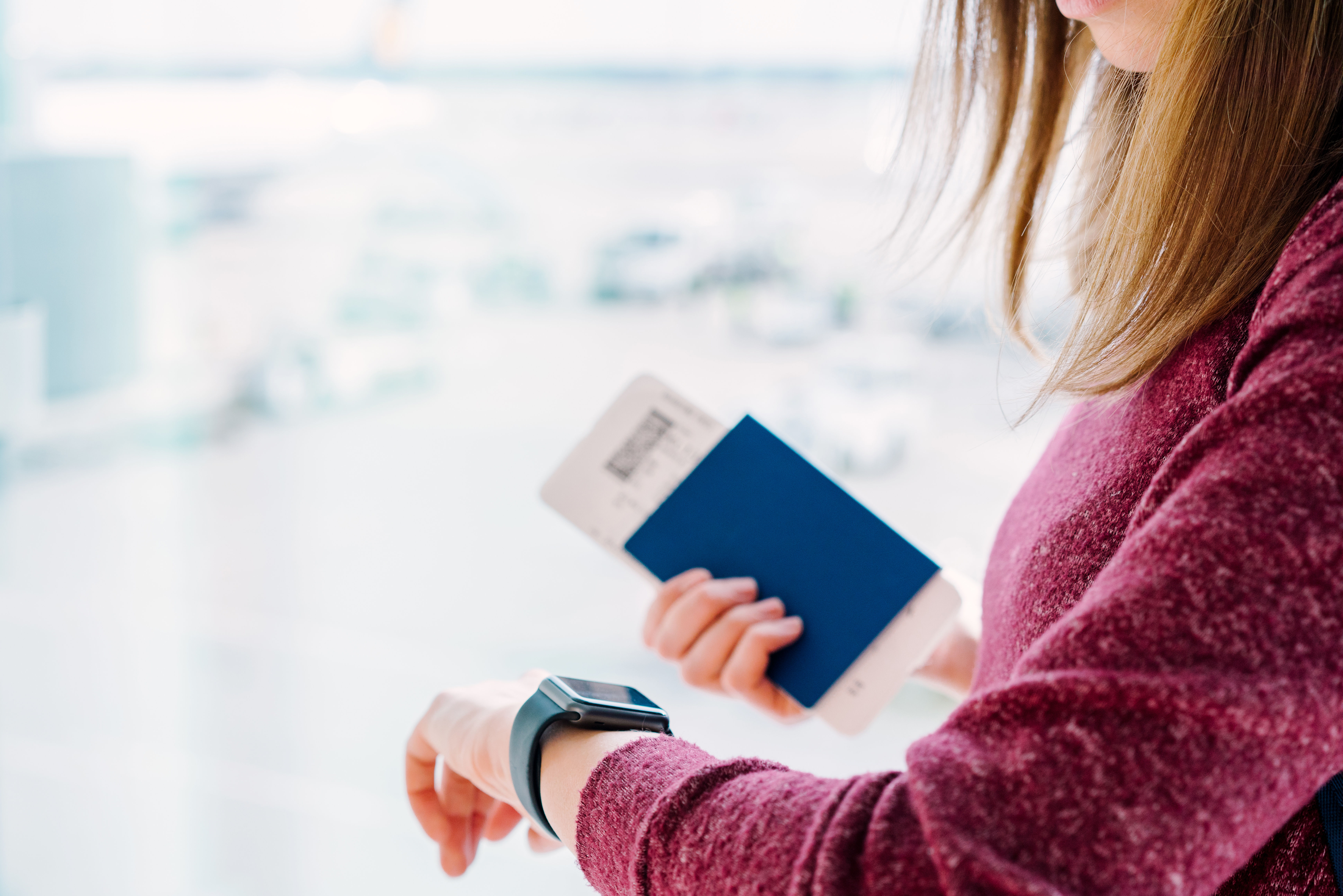 Woman checking time with her passport and boarding pass
