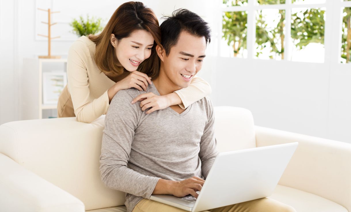 happy young couple using laptop on sofa